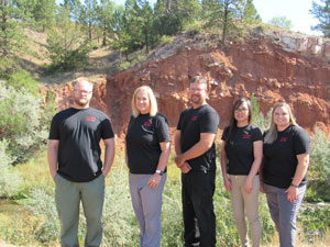 Picture of Fall River Health Services Rehabilitation Department Staff standing outside smiling. There is two males and three females standing next to one another. They are surrounded by pine trees and a red rock clay hill.