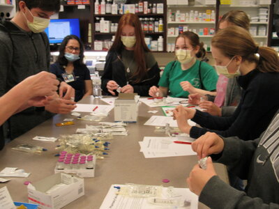 Picture of eight students sitting at a table doing some hands on at Scrubs Camp. 