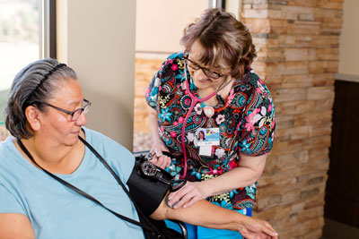 A nurse and a elderly lady is walking down a hall. 