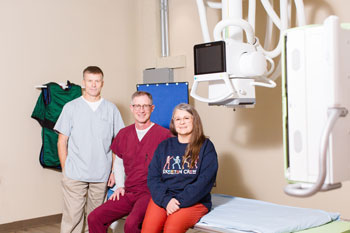 Picture of five Diagnostic Imaging Staff members standing and sitting near an MRI machine. 