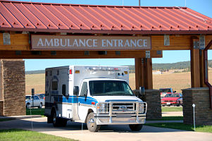 This is a picture of the Ambulance entrance with a blue and white ambulance sitting in the entrance 